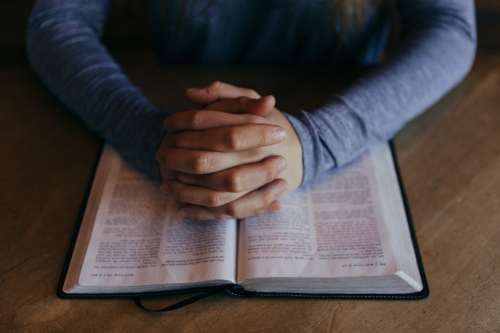 Hands Folded In Prayer over a Bible